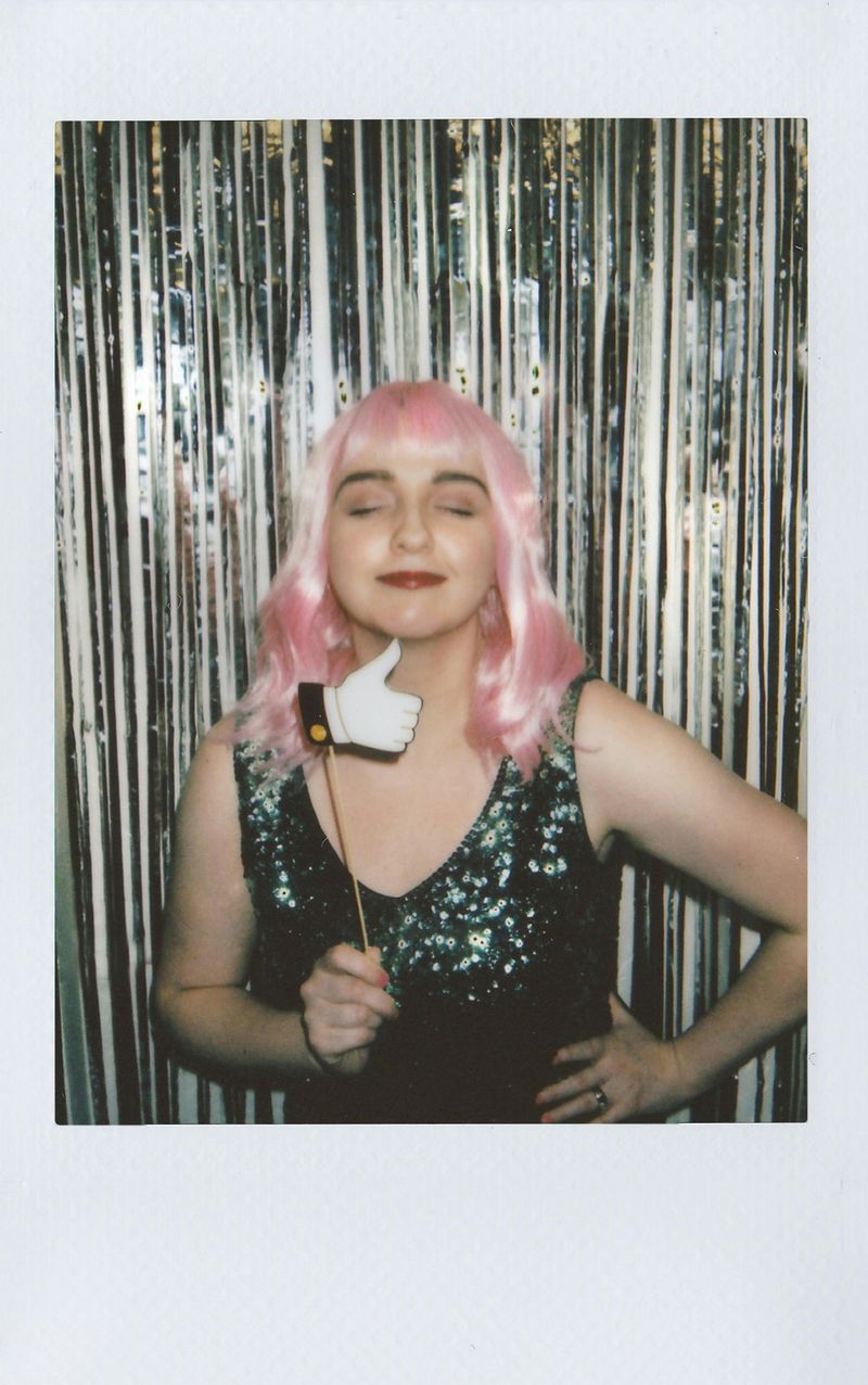 Guest in a pink wig posing with photo booth props