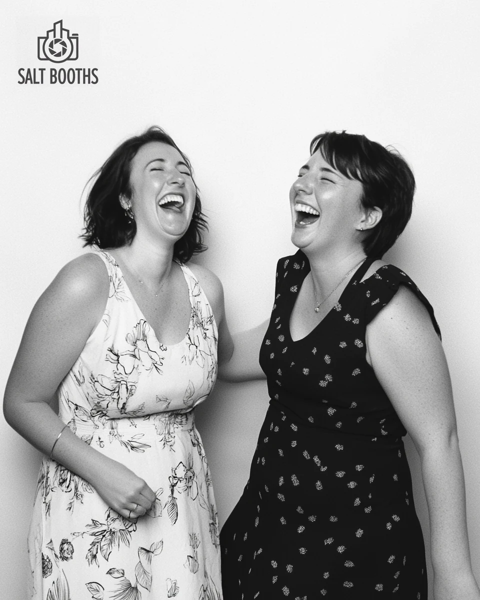 Two friends laughing in a black-and-white Glam booth portrait