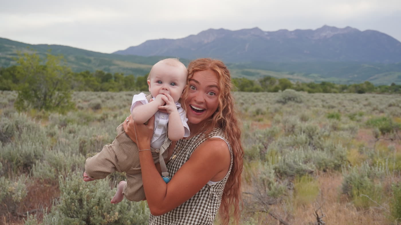 Wedding guest holding a baby in front of the mountain backdrop